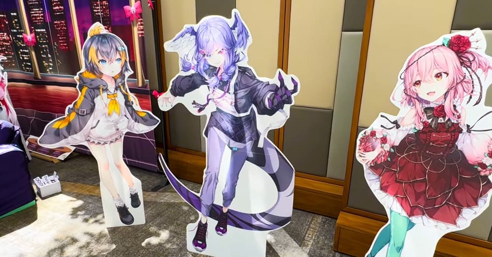 A screenshot from a YouTube video of OffKai Expo 2023, featuring cardboard cut-outs of Nijisanji EN Obsydia members Petra  Gurin, Selen Tatsuki, and Rosemi Lovelock